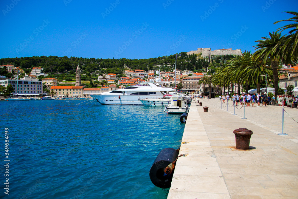 Waterfront promenade on the island of Hvar in Croatia - Luxury yacht moored in an old port of the Adriatic Sea