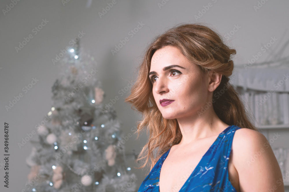 side view of beautiful confident woman with long hair looking away in front of white christmas tree side view of beautiful confident woman with long hair looking away in front of white christmas tree