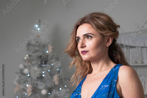 beautiful confident focused woman with long hair looking away in front of white christmas tree