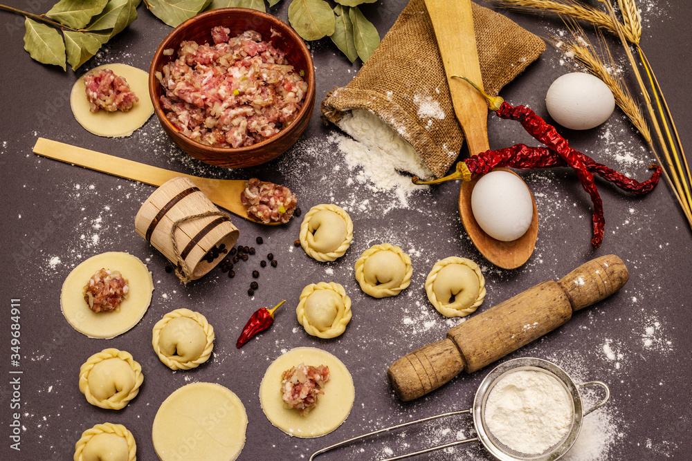 Composition with raw dumplings and ingredients on trendy black stone concrete background. Process of cooking Composition with raw dumplings and ingredients on trendy black stone concrete background. Process of cooking