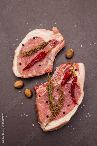 Raw pork steaks on trendy black stone concrete background