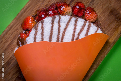 Tapioca filled with strawberries and chocolate . flatbread made from cassava also known as biju de tapioca. Beiju of tapioca, cassava-based dish typical Brazil. on green backgroud photo