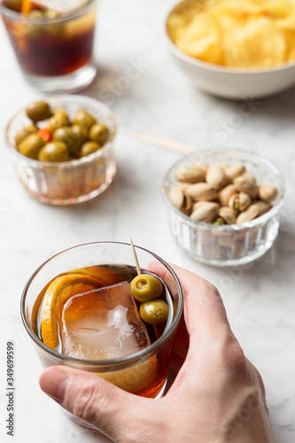 Man's hand grabbing a glass of vermouth from a marble table. Appetizer concept