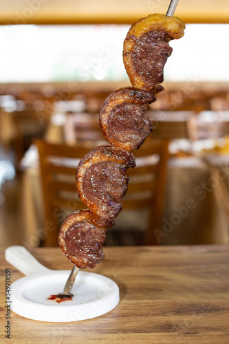 Picanha, traditional Brazilian barbecue, with defocused restaurant in the background