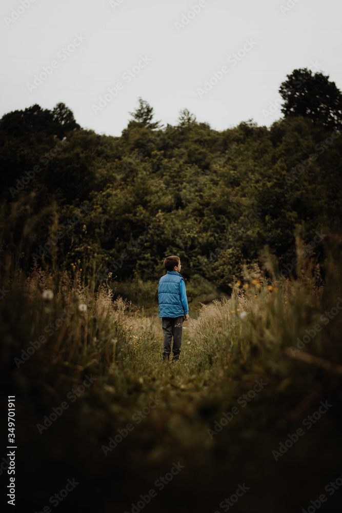 Little boy standing on the nature road and watching sky