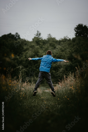 Happy little boy jumping on the road in nature 