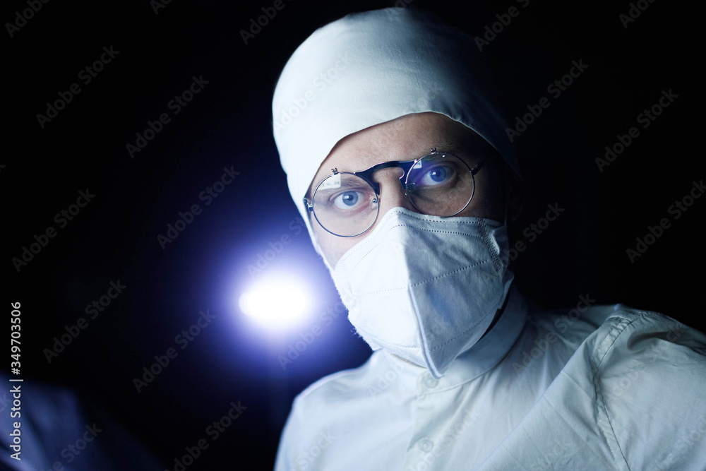 Male doctor scientist in uniform, glasses and a medical mask works at night in the office. professional look.