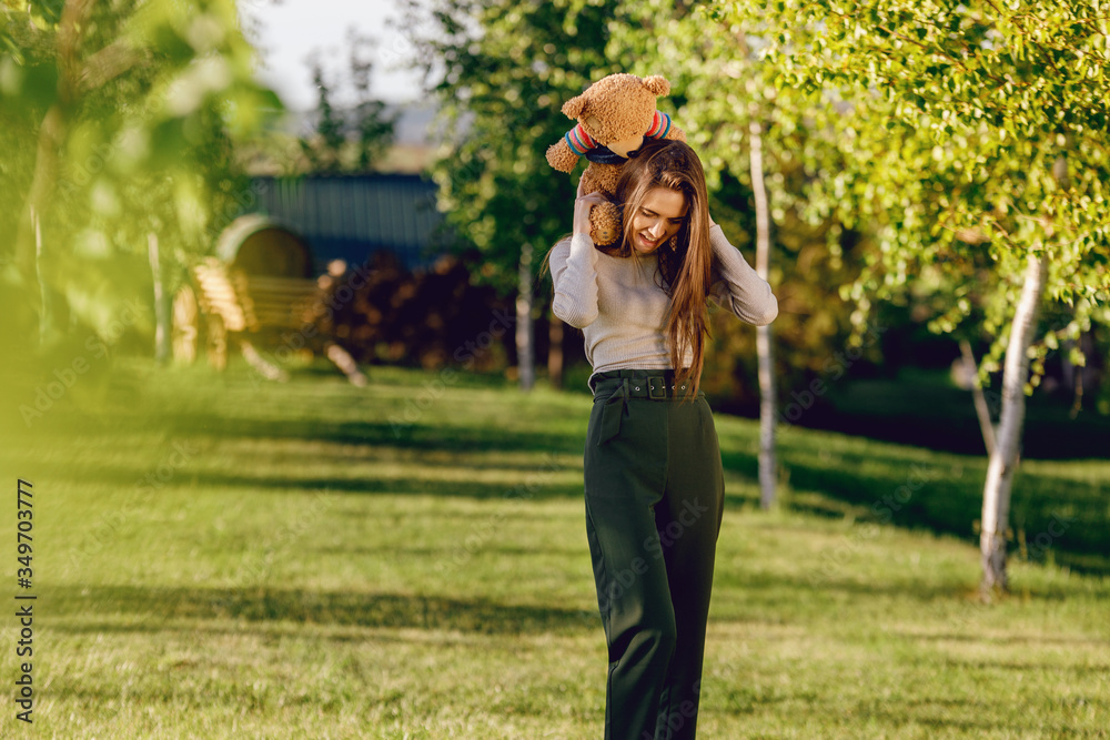 Obraz premium The girl hugs her bear against a background of nature.