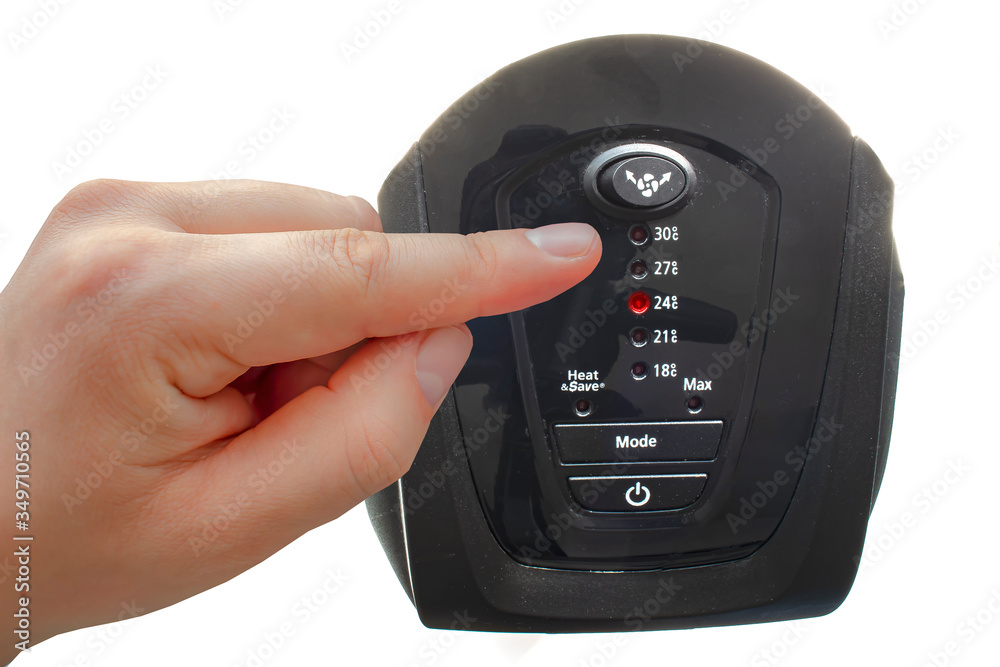 A person turning on a ceramic mini tower heater on a white background A person turning on a ceramic mini tower heater on a white background