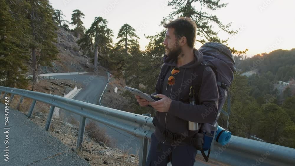 Tourist with backpack and tablet computer standing on road side Tourist with backpack and tablet computer standing on road side