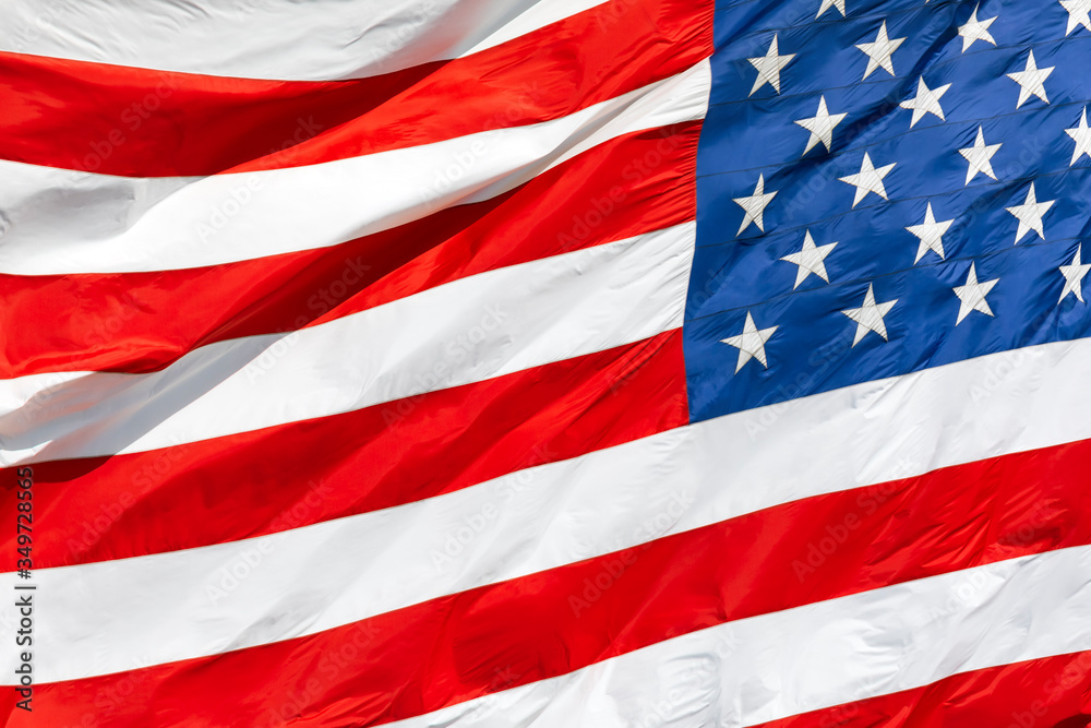 Obraz premium American flag waving in the wind, US flag motion close-up, red white blue flag outdoors in sunlight. United States of America national flag. USA stars and stripes