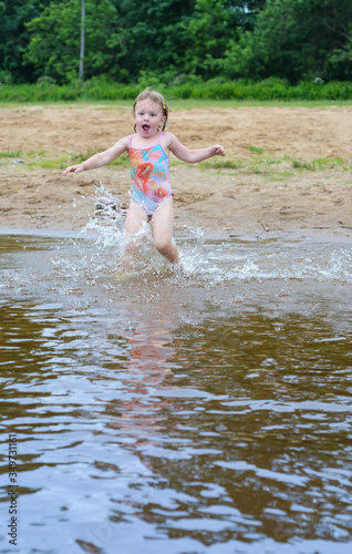 Fototapeta Naklejka Na Ścianę i Meble -  The girl runs into the water to swim.