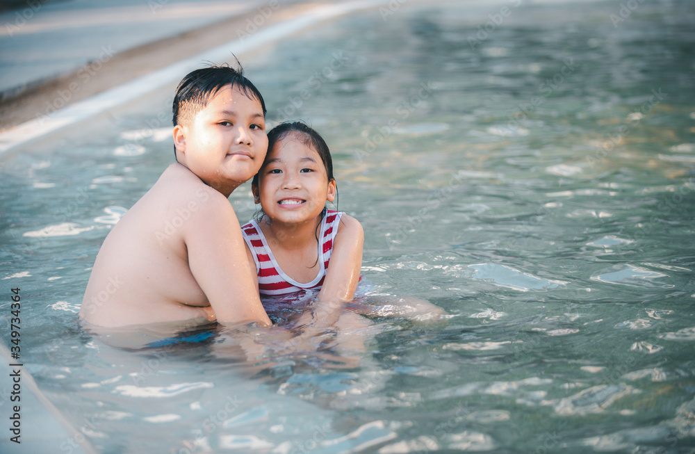 Happy brother and sisiter are playing water at swimming pool, Happy brother and sisiter are playing water at swimming pool,