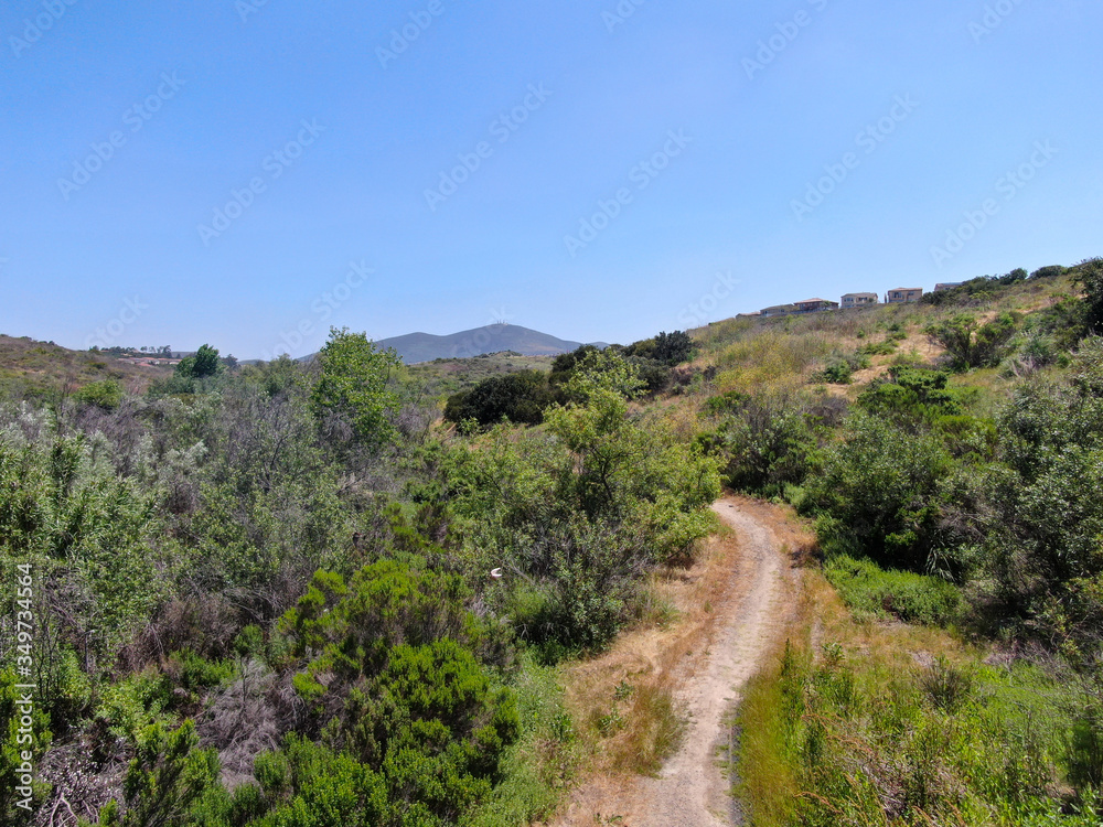 Aerial view of small dusty trail in green valley, San Diego, California, USA