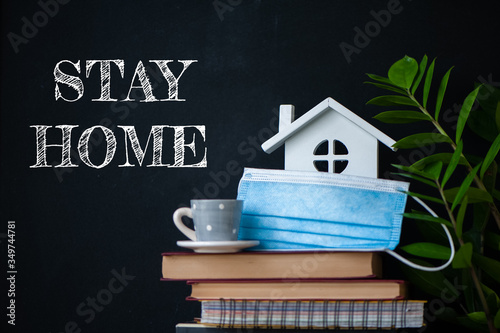 Stay home concept of selfisolation during the Covid-19 coronavirus pandemic. Cute home interior, house, books, flowers and the inscription - Stay home photo