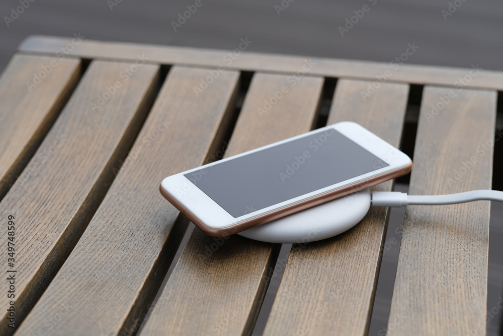 close up one smartphone on wireless charger on wooden table. blur background close up one smartphone on wireless charger on wooden table. blur background