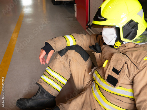 Firefighter sitting next to truck with mask and helmet to protect himself from the covid 19 photo