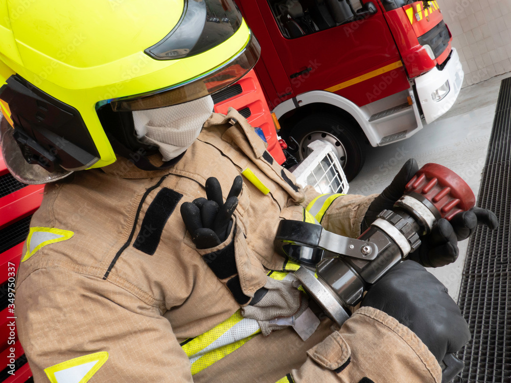 Firefighter holds the water lance, equipped with an intervention suit, helmet and mask to protect himself from covid 19. Firefighter holds the water lance, equipped with an intervention suit, helmet and mask to protect himself from covid 19.
