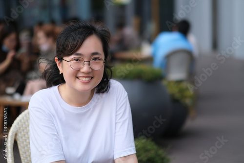 portrait of young Asian woman smiling and looking at camera at outdoor cafe. blur background