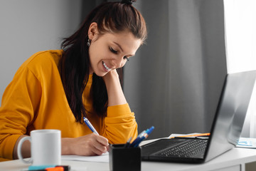 Beautiful girl using laptop studying at home, online education concept, studying science behind a laptop. Watching a webinar, looking for friends on social networks. Modern technologies.
