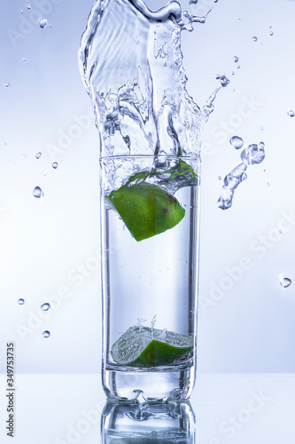 BASO DE AGUA CON LIMÓN Y GOTAS DE AGUA CONGELADAS EN EL AIRE  