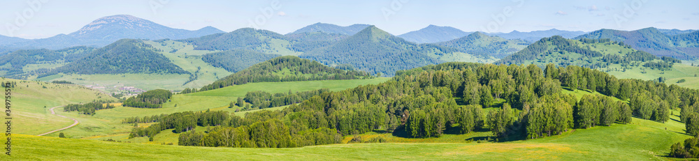 Panoramic mountain view. Bright sunlight, spring greens of forests and meadows. Panoramic mountain view. Bright sunlight, spring greens of forests and meadows.
