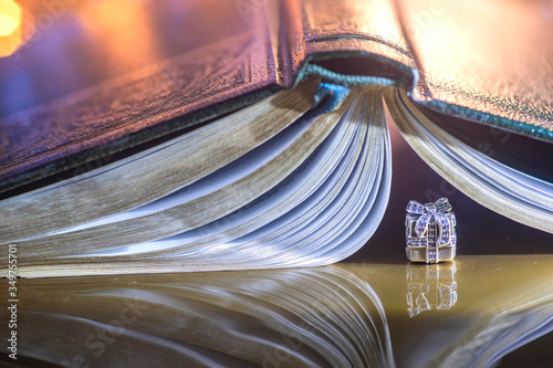 box with a gift on the background of book pages. silver decoration on the background of an open book. Vintage decoration and book. marriage proposal. love of reading