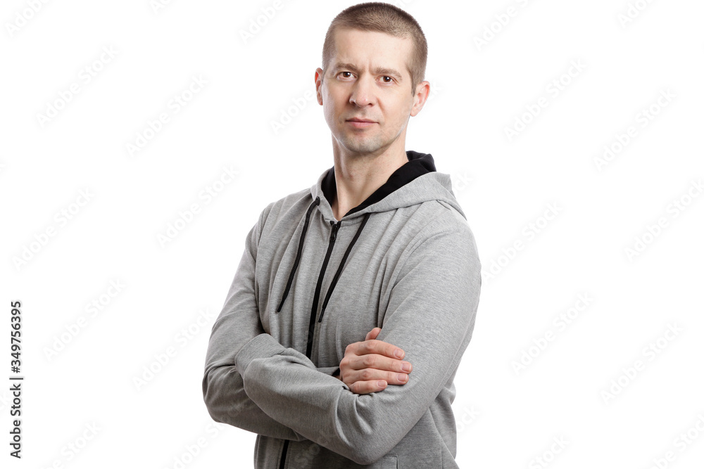 A sports confident athlete man, wearing a hooded jacket, crossed his arms on his chest, turned sideways. A look into the camera. Isolated A sports confident athlete man, wearing a hooded jacket, crossed his arms on his chest, turned sideways. A look into the camera. Isolated