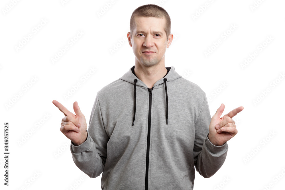 A sports confident athlete man, wearing a hooded jacket, smiles, his index finger points to the sides. A look into the camera. Isolated A sports confident athlete man, wearing a hooded jacket, smiles, his index finger points to the sides. A look into the camera. Isolated