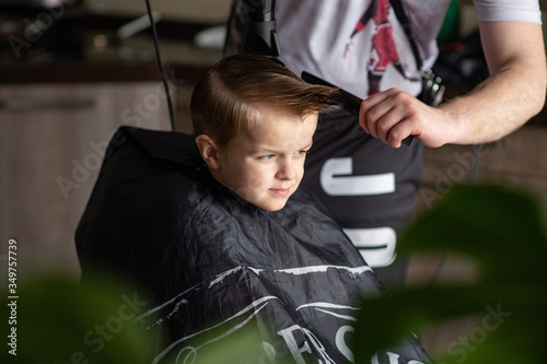 Barbershop and hairdressing at home. Men's and children's haircuts. The hairdresser cuts the boy. Stylish hairstyle for a child