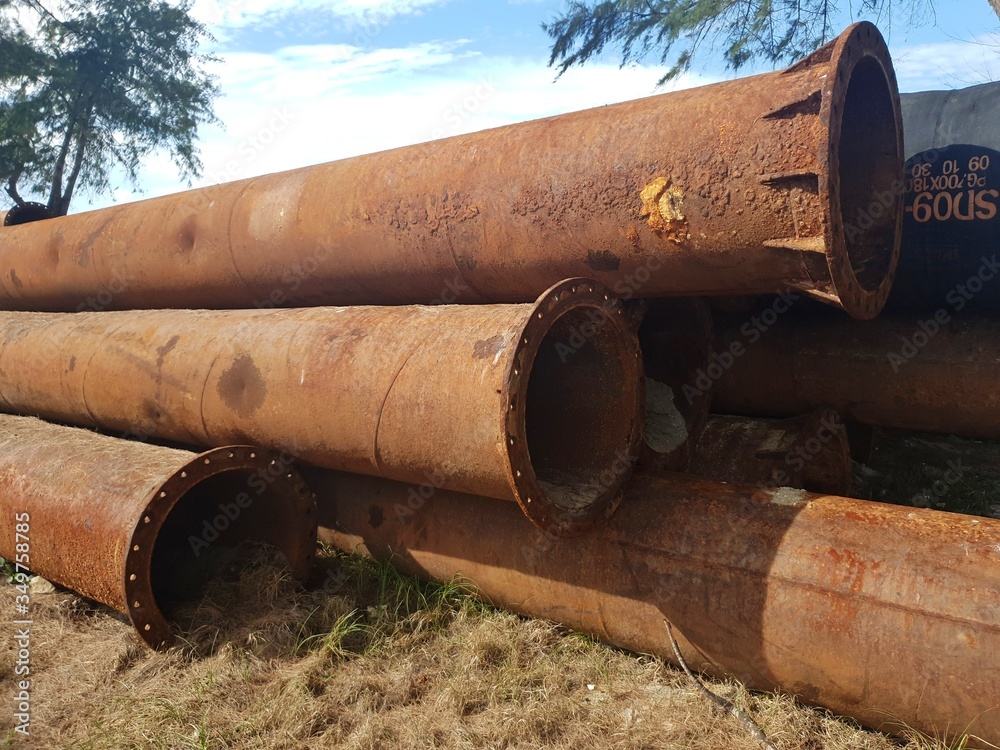 Stack of abandoned rustic pipeline laid on the sand beach Stack of abandoned rustic pipeline laid on the sand beach