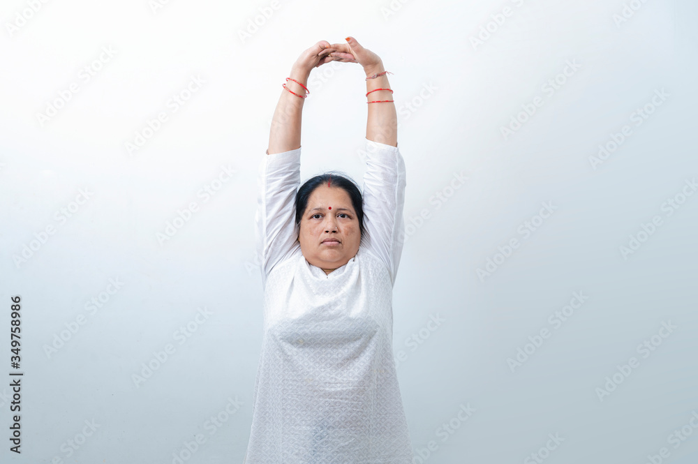 Middle Aged or an Old Indian Woman Performing Yoga Early Morning, in her house in white dress. Stay Home Stay Safe and Fit Middle Aged or an Old Indian Woman Performing Yoga Early Morning, in her house in white dress. Stay Home Stay Safe and Fit