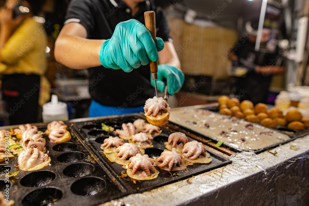 Blurry image Man doing octopus takoyaki Is a snack of Japanese people When chewing the squid, it feels crunchy, combined with the softness of the flour used to make it delicious.