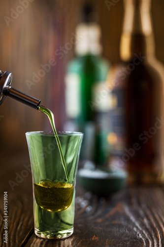 A green alcoholic drink is poured into a glass at a nightclub. at the bar. Preparation of a green cosmopolitan cocktail, shallow depth of field, selective focus. photo