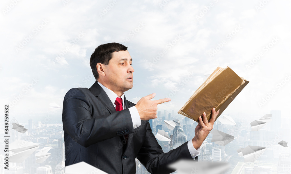 Senior businessman finger pointing into open book Senior businessman finger pointing into open book