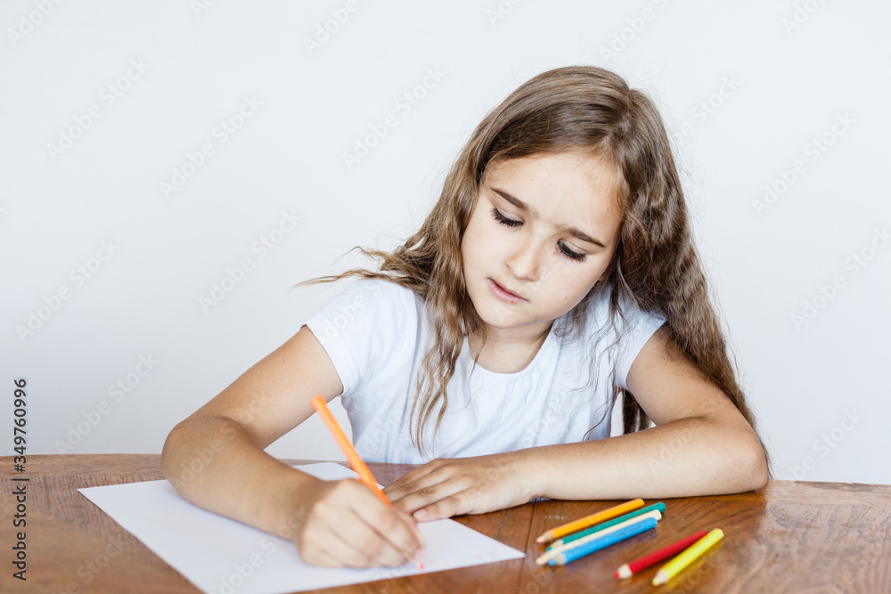 The girl draws in a notebook, writes letters, colored pencils, classes at home, online training, development of mental intelligence The girl draws in a notebook, writes letters, colored pencils, classes at home, online training, development of mental intelligence