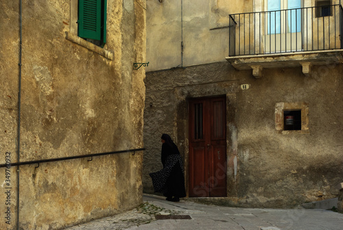 An elderly woman with the characteristic dress, with small steps, walks through the streets of the village. Scanno, Abruzzo, Italy. © Enrico Spetrino