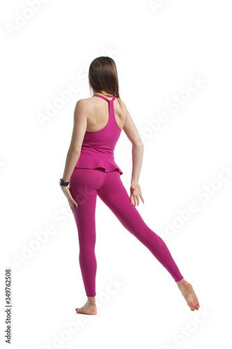 Slender girl in pink sportswear isolated from white background view from the back.