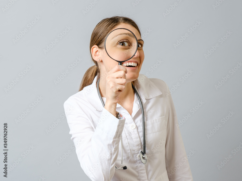 Portrait of beautiful female doctor looking through loupe Portrait of beautiful female doctor looking through loupe