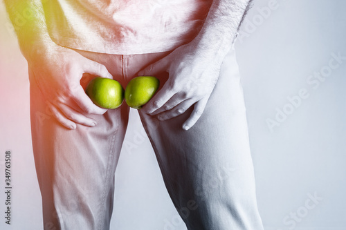 The man spread his legs and at the level of the genitals holding a ripe and rotten Apple. Disease for men. The concept of protection against sexually transmitted infections. Black and white color photo