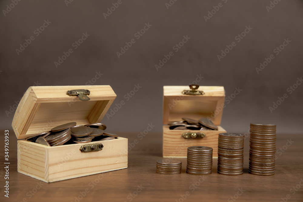 Many coins are stacked in a graph shape and many coins in a wooden crate for money saving ideas financial planning and insurance. Many coins are stacked in a graph shape and many coins in a wooden crate for money saving ideas financial planning and insurance.