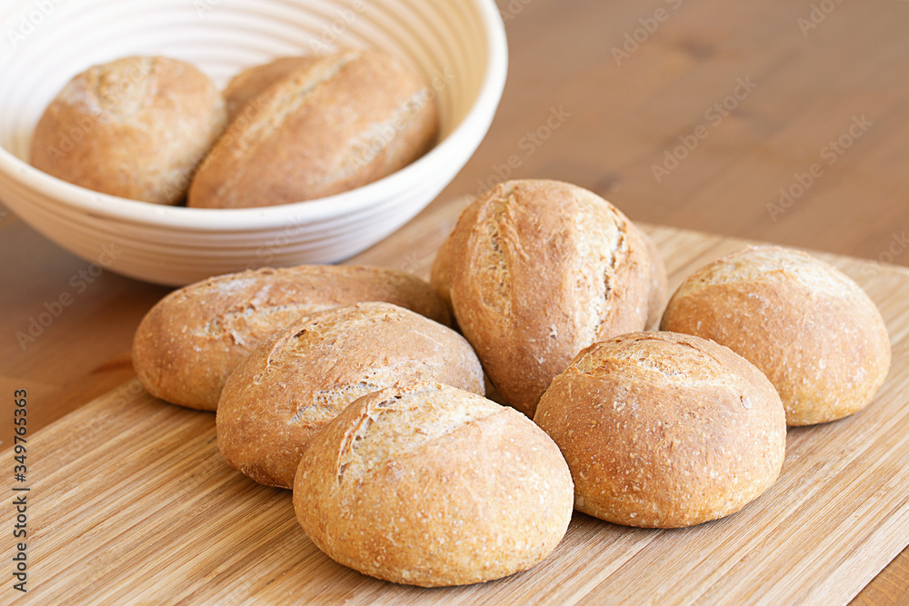 Small round and oval homemade breakfast buns lie on the kitchen table in daylight indoors, a good option for a healthy breakfast or snack.
