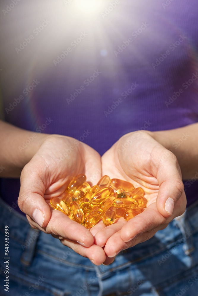 A handful of vitamin d capsules are in women's hands. Blurred background A handful of vitamin d capsules are in women's hands. Blurred background