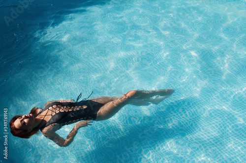 fashion photo of a sexy beautiful girl in elegant bikini posing and takes a sunbath in the swimming pool