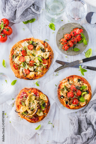 gourmet pizza with tomatoes, olives and basil leaves on wooden table