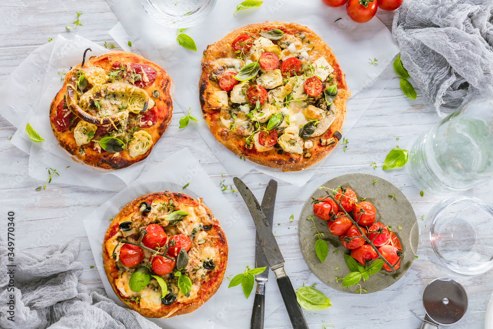 gourmet pizza with tomatoes, olives and basil leaves on wooden table gourmet pizza with tomatoes, olives and basil leaves on wooden table