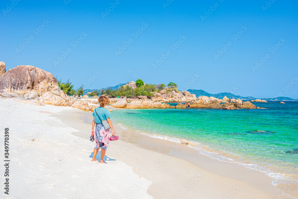 Woman looking at view in tropical beach. Vietnam travel destination, Phu Yen province between Da Nang and Nha Trang. Gorgeous sand beach with boulders and blue waving sea Woman looking at view in tropical beach. Vietnam travel destination, Phu Yen province between Da Nang and Nha Trang. Gorgeous sand beach with boulders and blue waving sea
