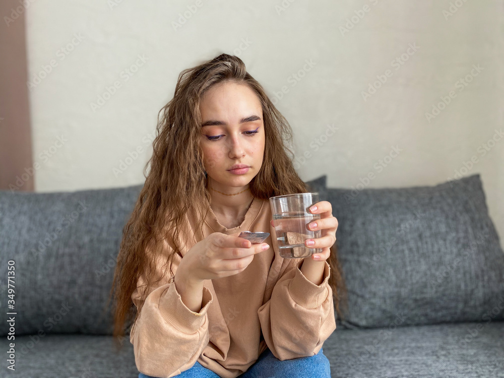 Depression a young woman with long hair is sitting on the sofa in her living room. Depression a young woman with long hair is sitting on the sofa in her living room.