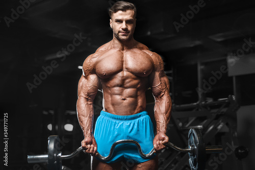 Bodybuilder strong man pumping up biceps muscles