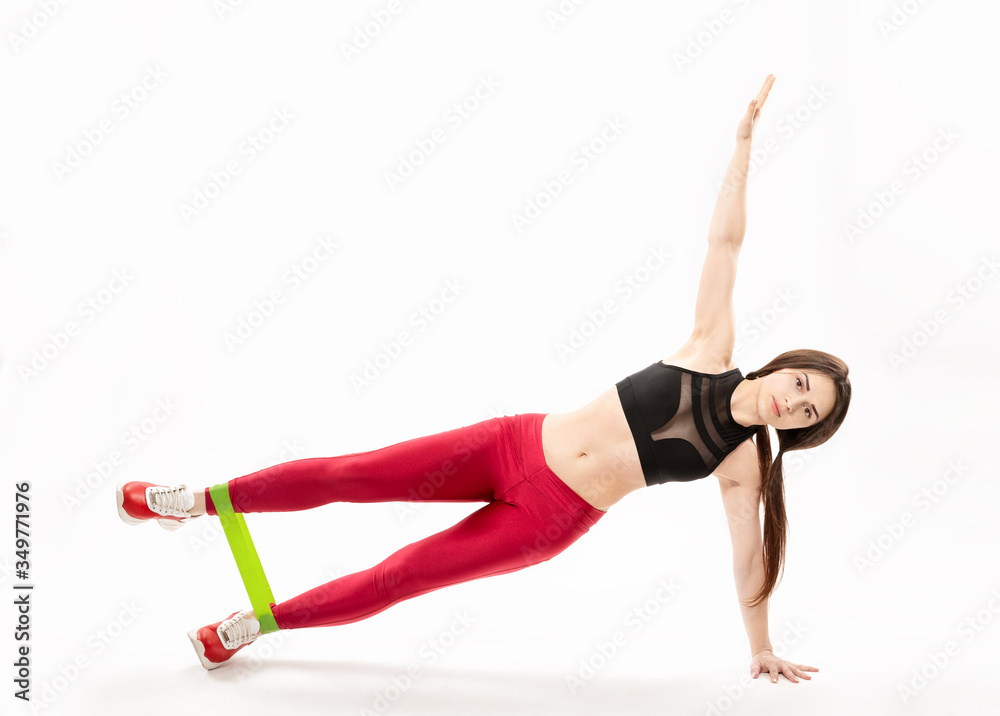 young, slim girl doing sport exercises with rubber expander isolated on white background